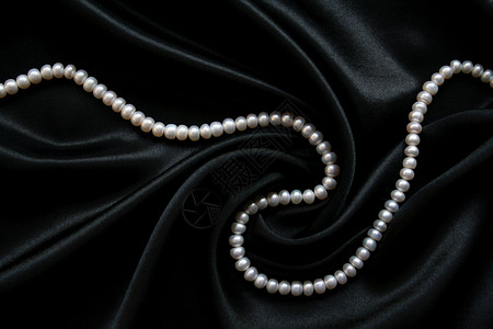 黑丝上的白珍珠白色礼物细绳宝石珠子女性化手镯丝绸宝藏天鹅绒背景图片