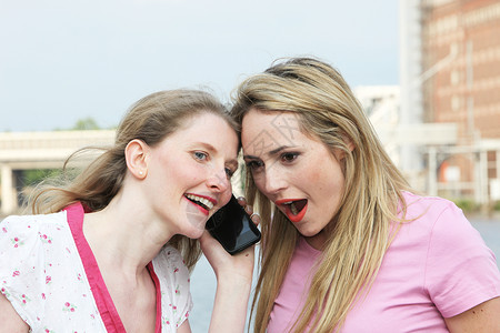 两位女士在听一个手机背景图片