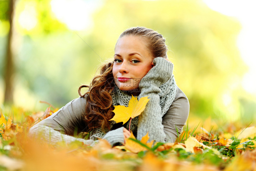 秋叶中的妇女脚尖季节头发毛衣乐趣叶子公园成人团体金发女郎橙子图片