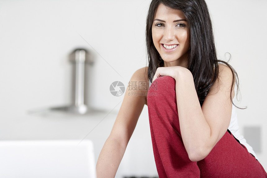 在家用笔记本电脑的年轻妇女女士休息柜台女孩网络社交微笑女性厨房台面图片