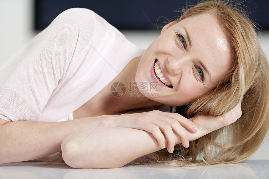 年轻妇女坐在桌子上快乐休息室女士粉色微笑厨房餐桌女性休息衬衫图片