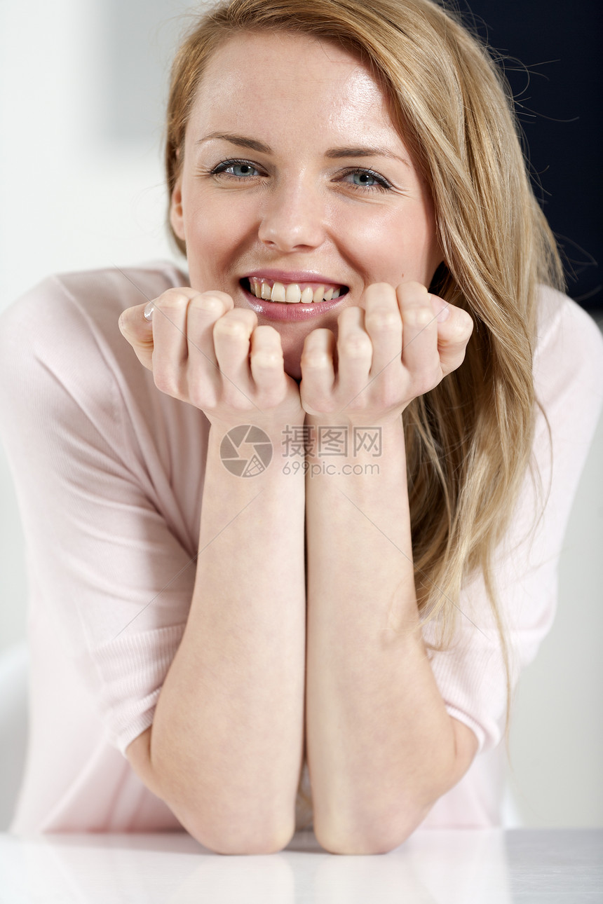 年轻妇女坐在桌子上厨房粉色微笑快乐休息餐桌女性衬衫休息室女士图片