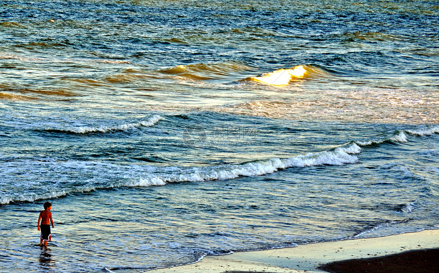 男孩在波浪中漫步蓝色天空男性伙计海浪男生儿子贝壳海洋推介会图片