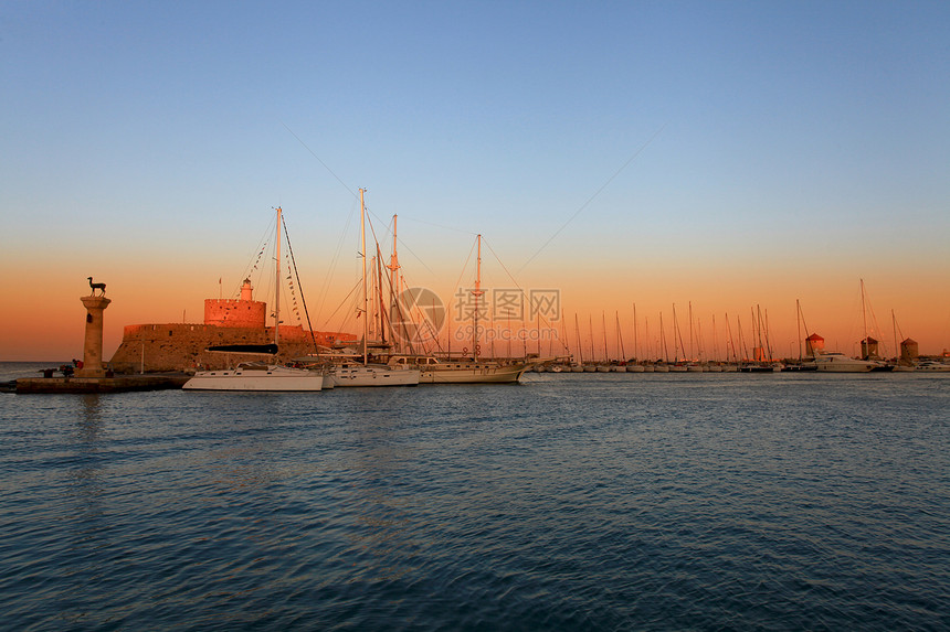 日落时 希腊的罗得港和风车码头雕像纪念碑天空地标海洋玫瑰旅游日出海景图片