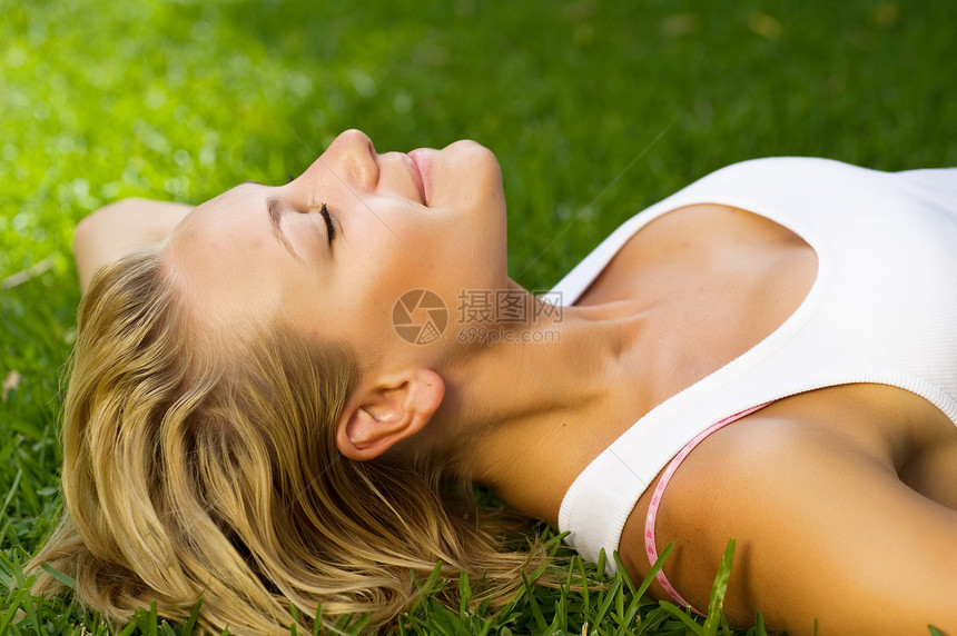 美丽的健康年轻女孩躺在绿草上 躺着自由场地女士幸福时间草地太阳日落福利女性图片