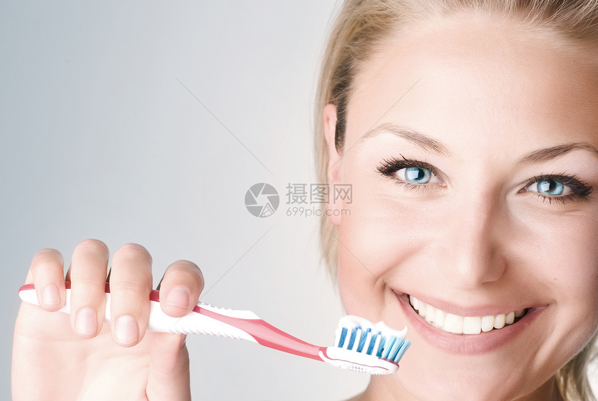 快乐的青年女子刷牙幸福白色牙刷女士牙科牙齿金发刷子头发女性图片