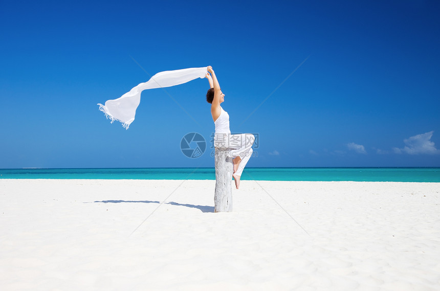 在海滩上快乐的女人阳光海洋热带天空乐趣享受自由围裙女性晴天图片