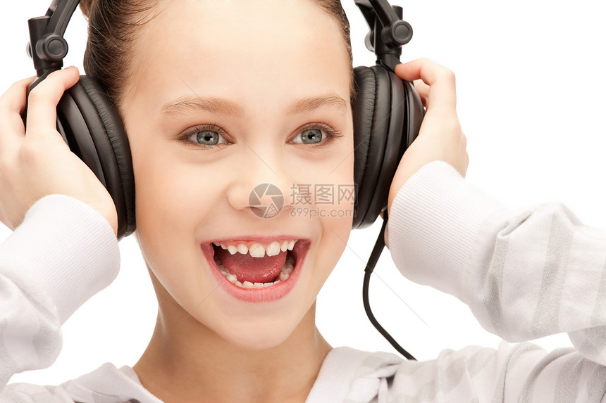 使用大耳机的快乐少女喜悦耳机女性青少年乐趣手机微笑音乐播放器听力享受图片