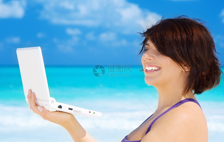 海滩上拥有膝上型电脑的妇女电子邮件中年互联网上网假期快乐自雇旅行笔记本微笑图片