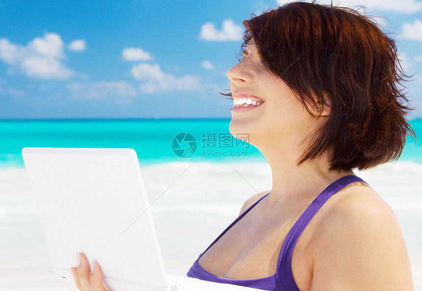 海滩上拥有膝上型电脑的妇女假期自雇晴天海洋上网互联网天空技术蓝色旅行图片