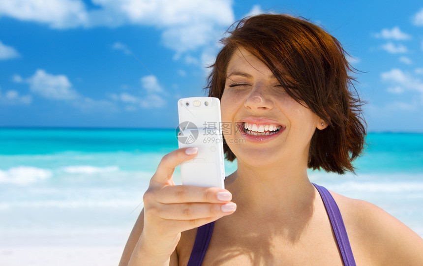 在海滩上有电话的快乐女人邮件天空呼唤闲暇阅读冲浪细胞网络技术手机图片
