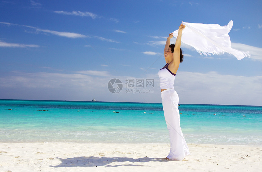 带着白沙龙的快乐女人享受晴天天堂天空海滩蓝色海洋中年旅行海岸图片