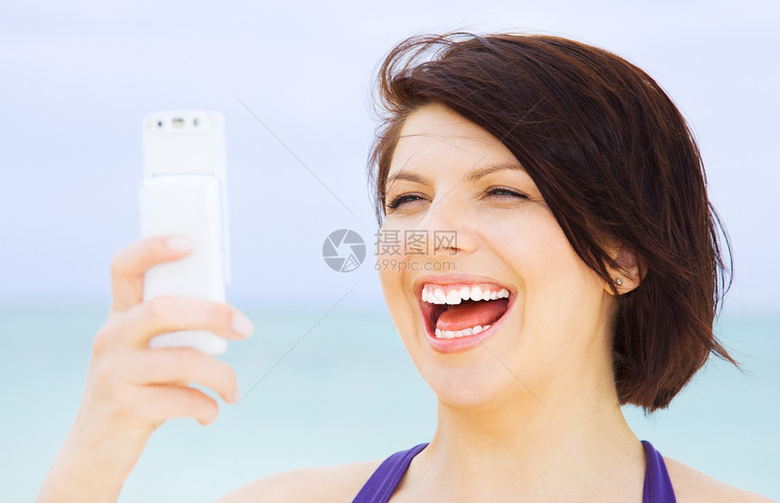 在海滩上有电话的快乐女人闲暇天空上网网络互联网微笑冲浪电子邮件细胞技术图片