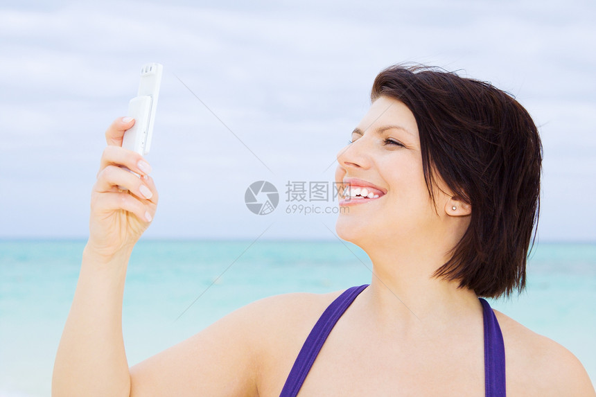 在海滩上有电话的快乐女人短信细胞互联网技术微笑上网八卦网络冲浪邮件图片