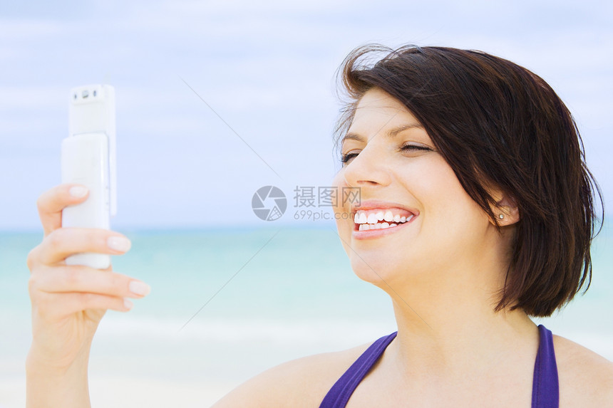 在海滩上有电话的快乐女人技术电子邮件闲暇呼唤网络上网微笑阅读天空互联网图片