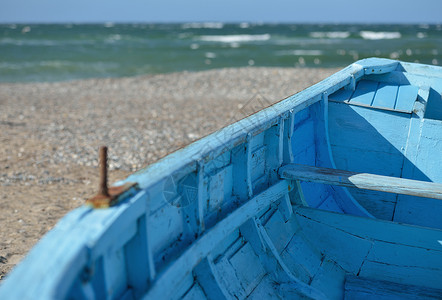 海滩上的蓝船浅蓝色波浪孤独天空静物碎石蓝色石头木头旅行背景图片