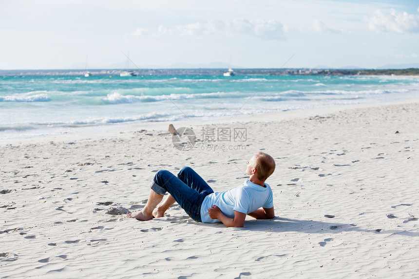 青年男子在暑假的沙滩上放松海岸力量天空海洋假期蓝色阳光旅行旅游身体图片