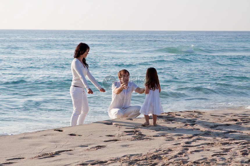 快乐的年轻家庭 和女儿在沙滩上团体父母成人母亲乐趣蓝色男性海滩喜悦旅游图片