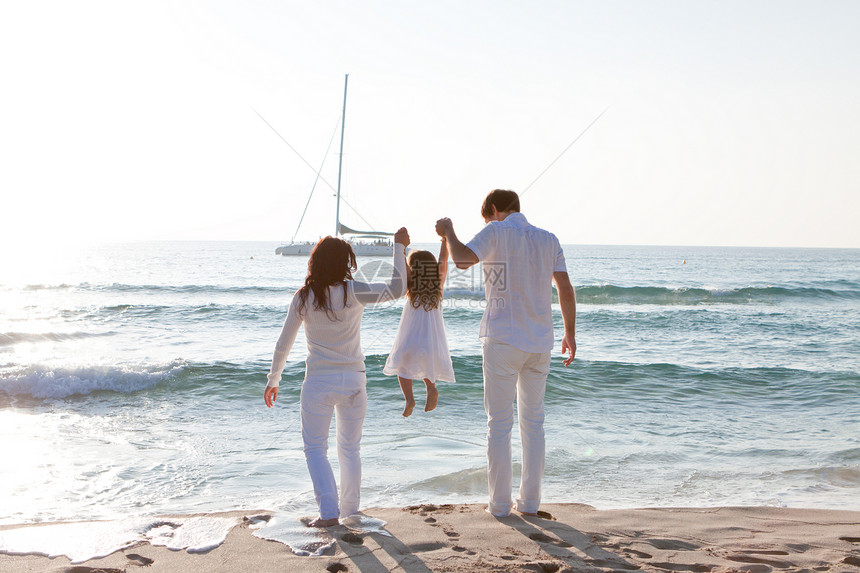 快乐的年轻家庭 和女儿在沙滩上喜悦男性团体孩子父母乐趣旅行成人海滩幸福图片