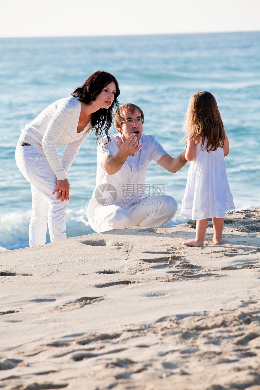 快乐的年轻家庭 和女儿在沙滩上父母海滩旅行假期旅游男性父亲女性女孩蓝色图片