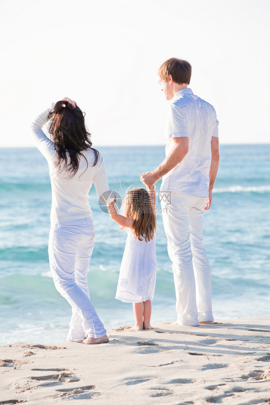 快乐的年轻家庭 和女儿在沙滩上团体男性父母旅行母亲幸福蓝色海滩旅游女性图片