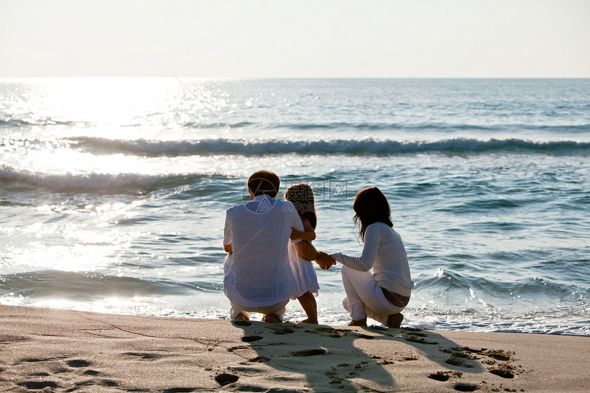 快乐的年轻家庭 和女儿在沙滩上父母喜悦乐趣母亲孩子女士海滩成人男人女孩图片