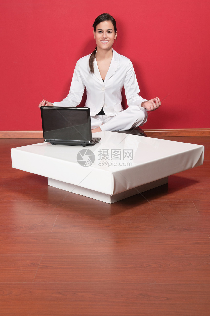 坐在瑜伽莲花位置的漂亮女商务人士图片