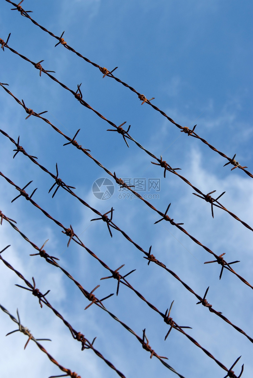 铁丝栅栏和蓝天空伤害边界防御铁丝网危险蓝色天空农场疼痛金属图片