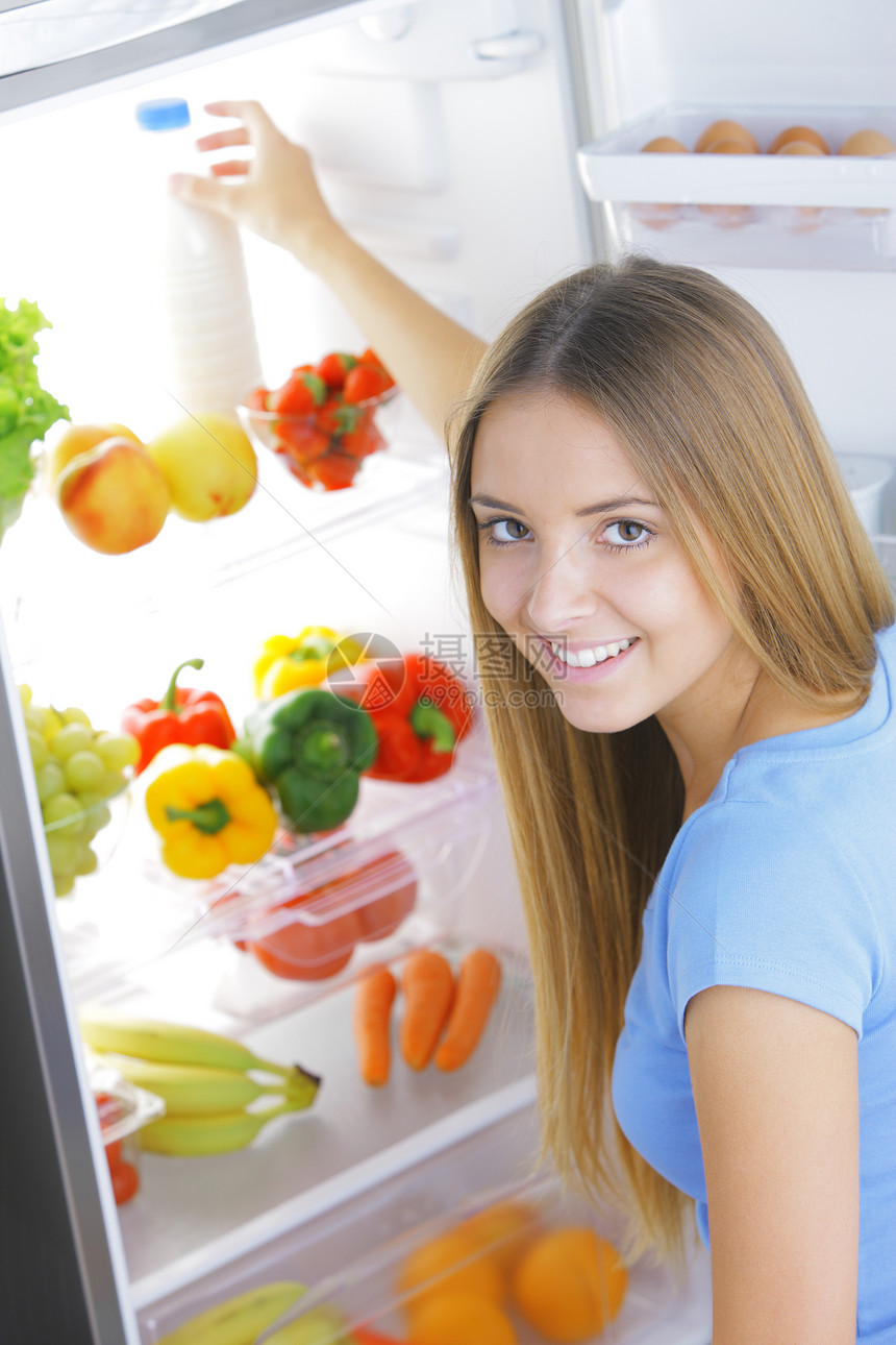 冰箱中的牛奶生活瓶子女士金发女郎蓝衬衫饮食蔬菜水果表达微笑图片