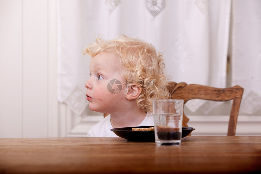 好奇的年轻男孩在餐桌图片