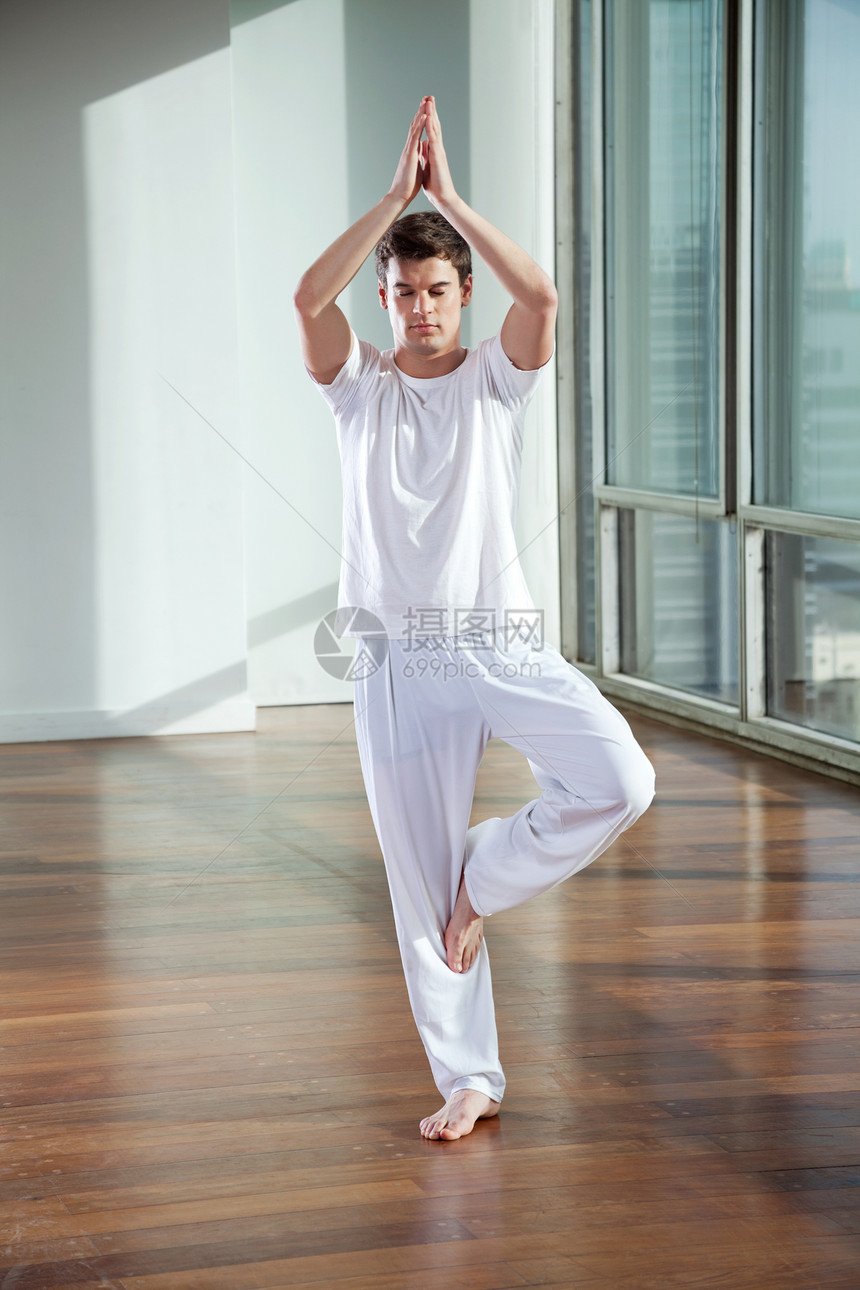 年青男子练瑜伽冥想平衡姿势男人训练沉思练习专注眼睛健身房图片
