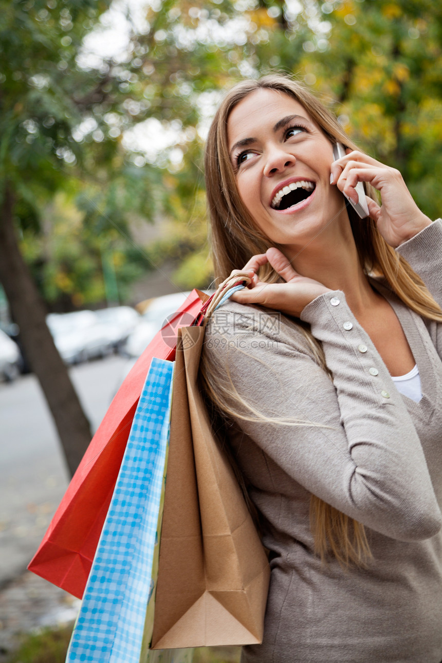 妇女携带购物袋时被叫来闲暇手机讲话成人女孩金发头发购物幸福电话图片