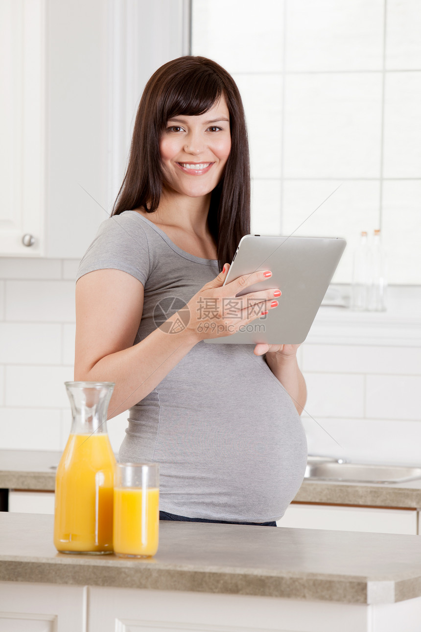 厨房的怀孕妇女微笑橙子腹部技术女性电脑妈妈肚子母性黑发图片