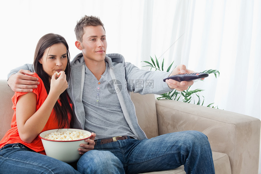 一对一对坐在一起的情侣 一起拥抱着他们看电视 吃爆米花图片