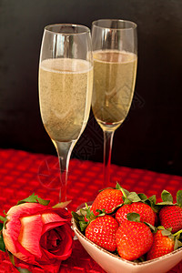盛满香槟的杯子和草莓 在碗里 一朵玫瑰背景图片