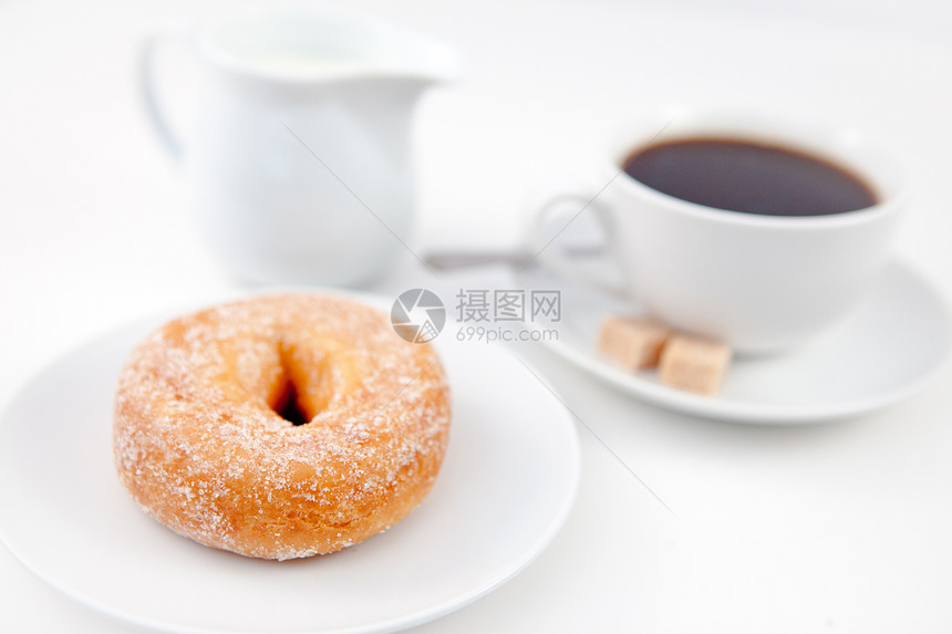 甜甜圈加糖霜和一杯咖啡放在白盘子上图片