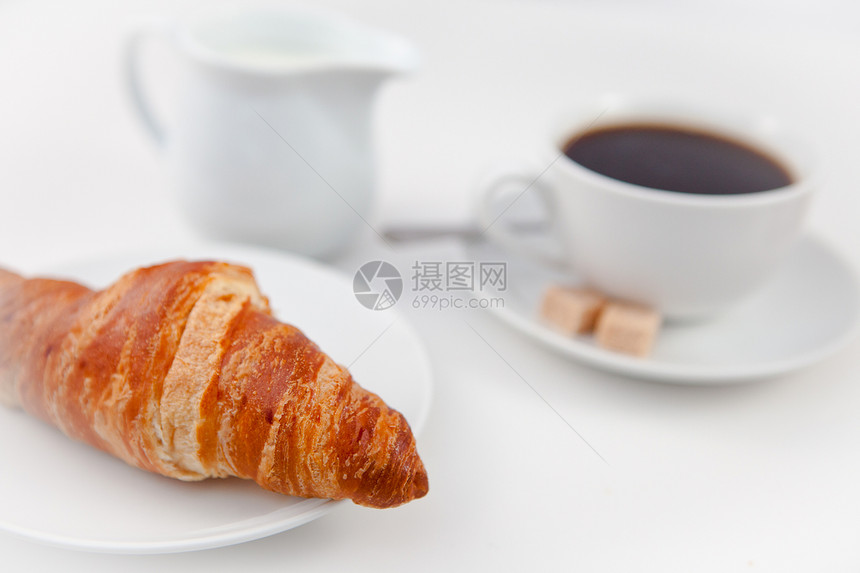 Croissant 和一杯咖啡 在白盘上加糖和牛奶图片