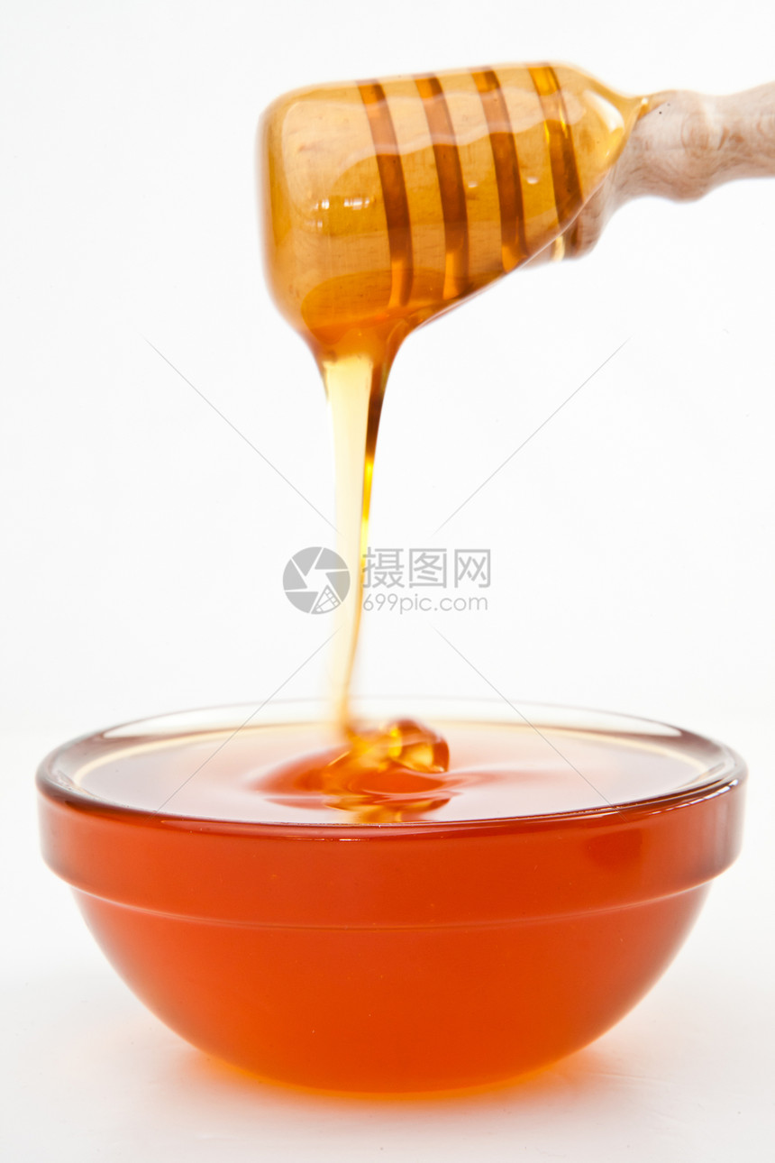 蜂蜜在蜂蜜的花朵上 滴在碗里图片