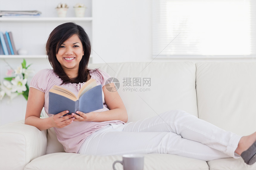 女人躺在沙发上拿着一本书图片
