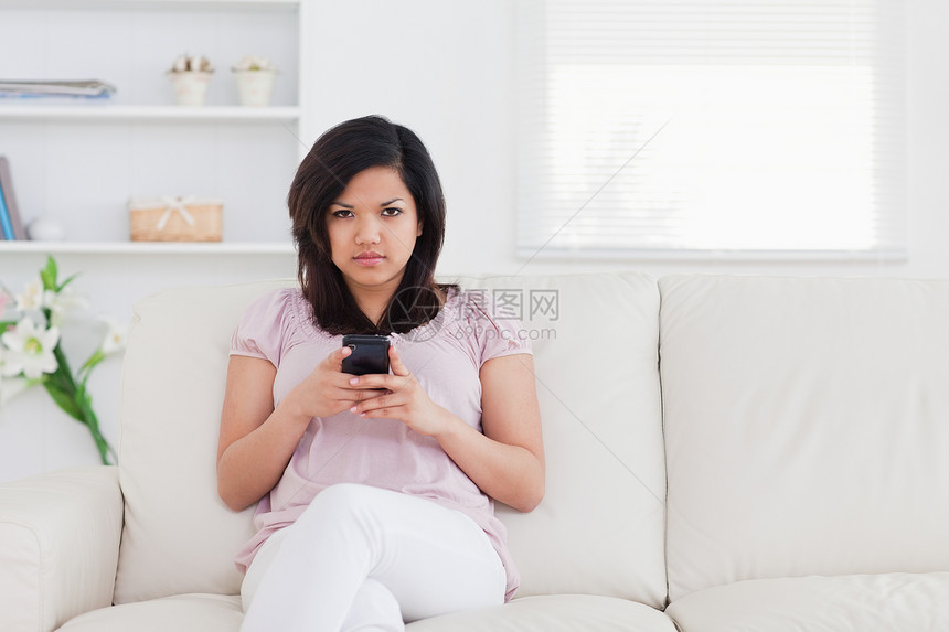 妇女坐在沙发上 同时拿着电话图片