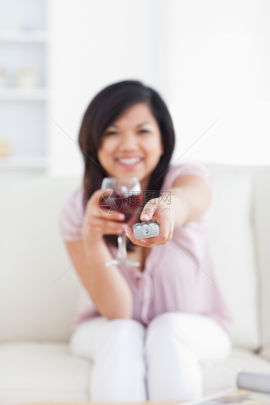 妇女一边拿着电视遥控器一边喝杯酒 一边喝酒图片