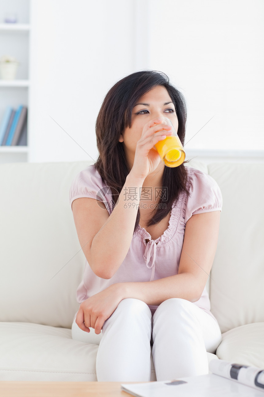 女人坐在沙发上喝杯橙汁 却又坐着在沙发上图片