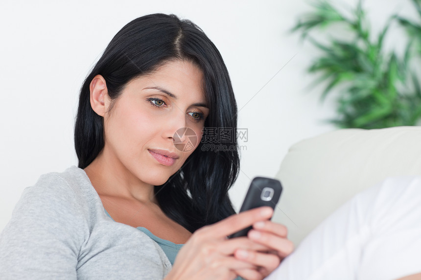 女人坐在沙发上时用电话打字图片