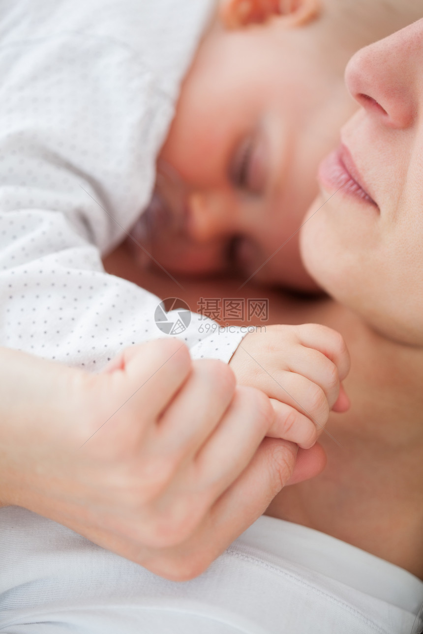 平和的女人和她的孩子躺在一起 她正在吸一个奶嘴图片