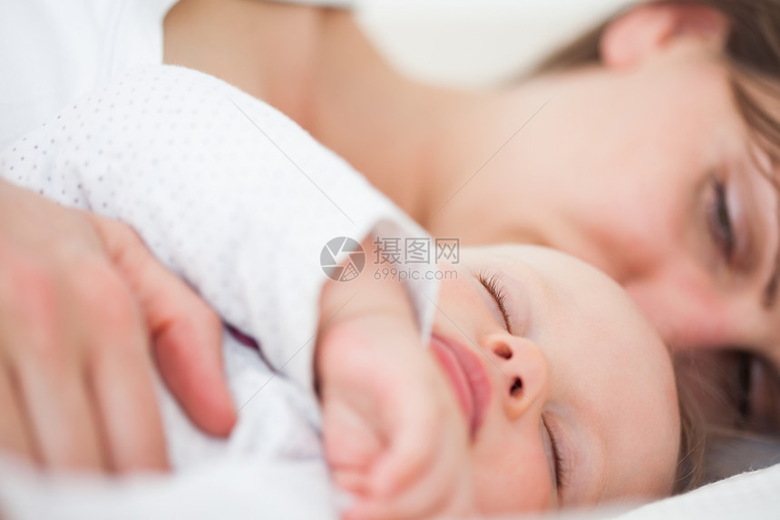 女人和她的婴儿并肩躺着图片