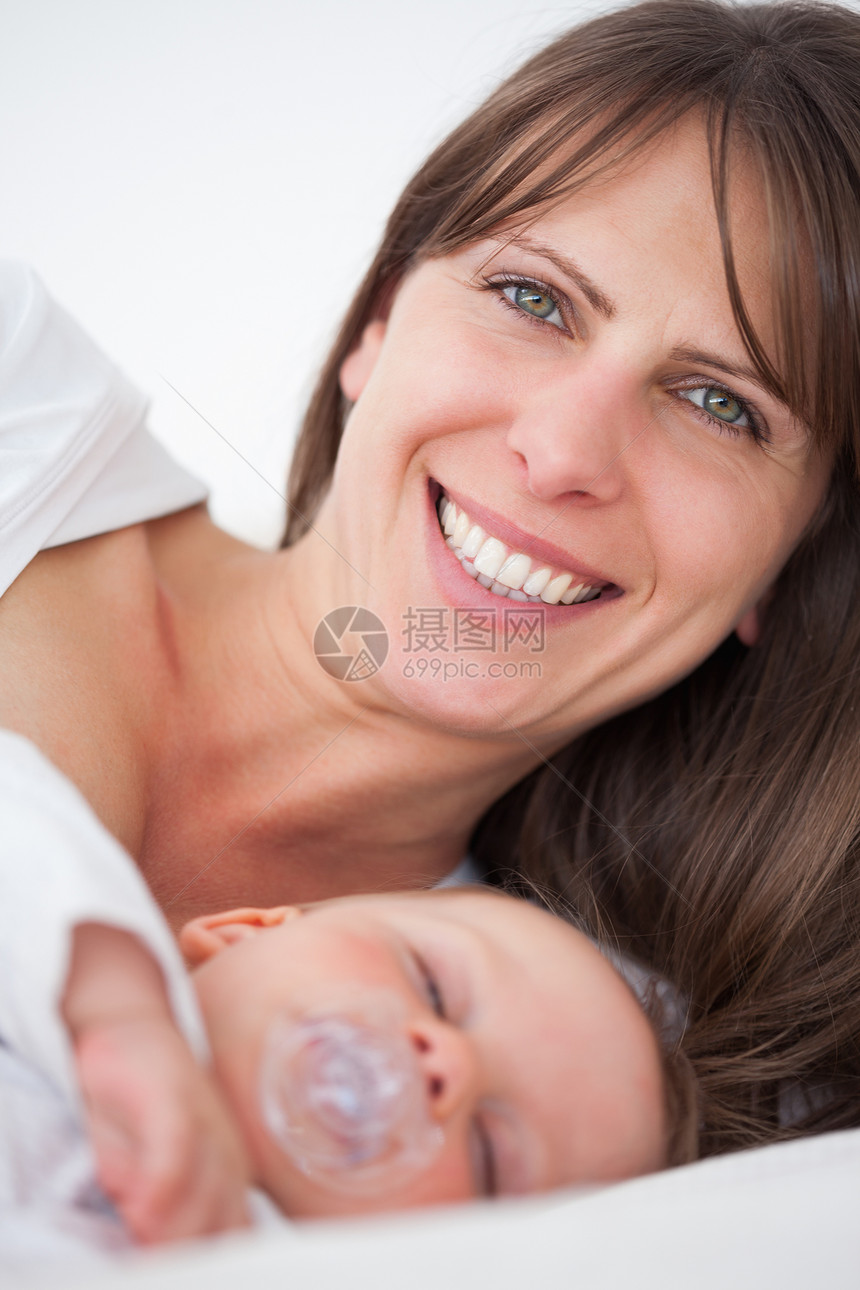 在婴儿睡觉时躺着微笑的黑发女人图片