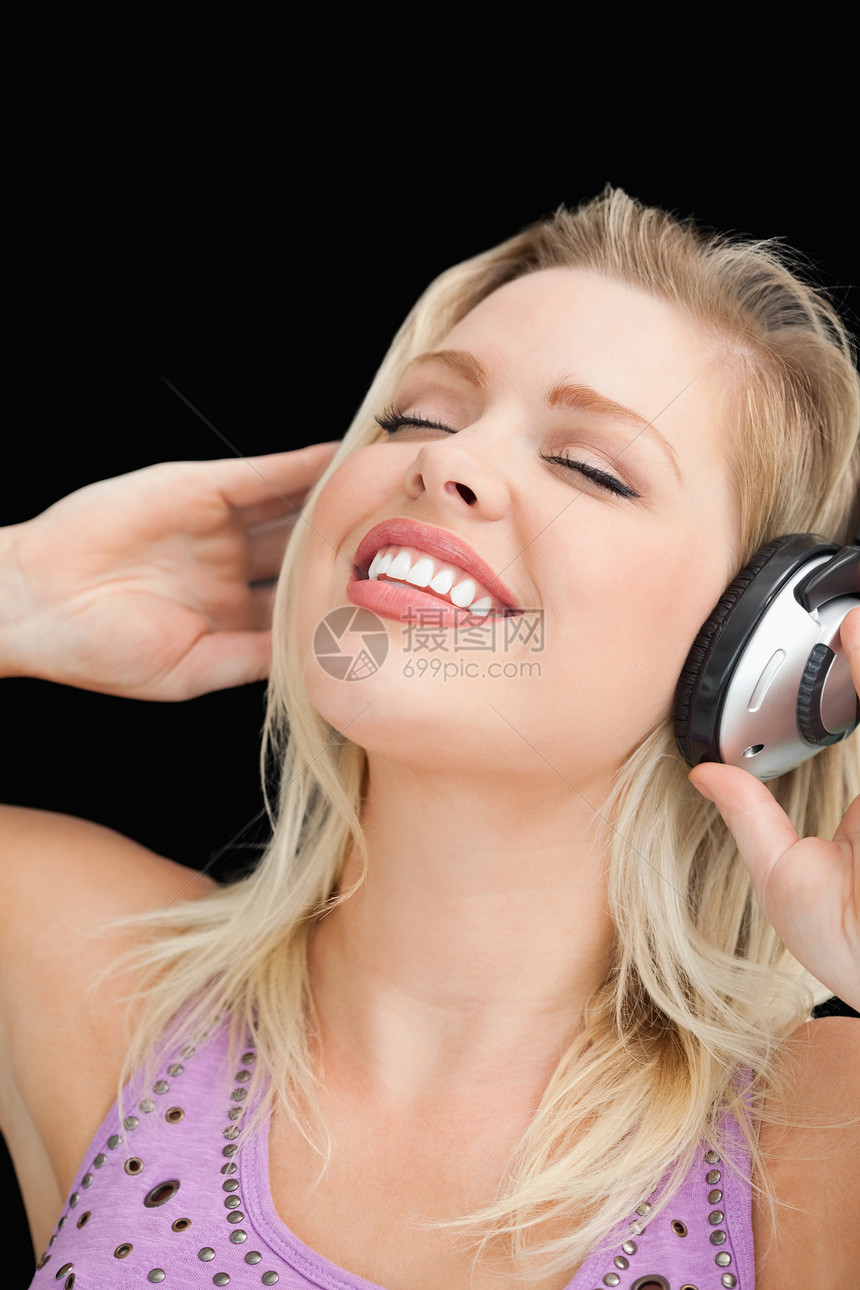 快乐的金发金发女人 用耳机听音乐耳朵黑色金发女郎听力女性女士长发配售眼睛背景图片