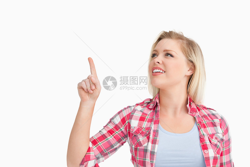 金发女人在指着她的手指时微笑图片