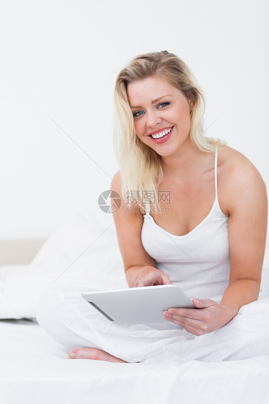金发美女在拿着一本电子书时微笑图片