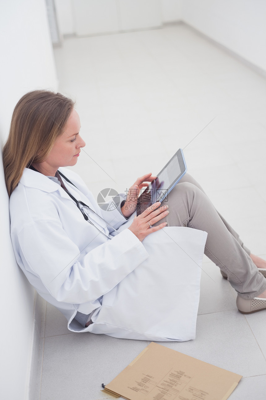 坐在地板上拿着数字平板电脑的医生图片